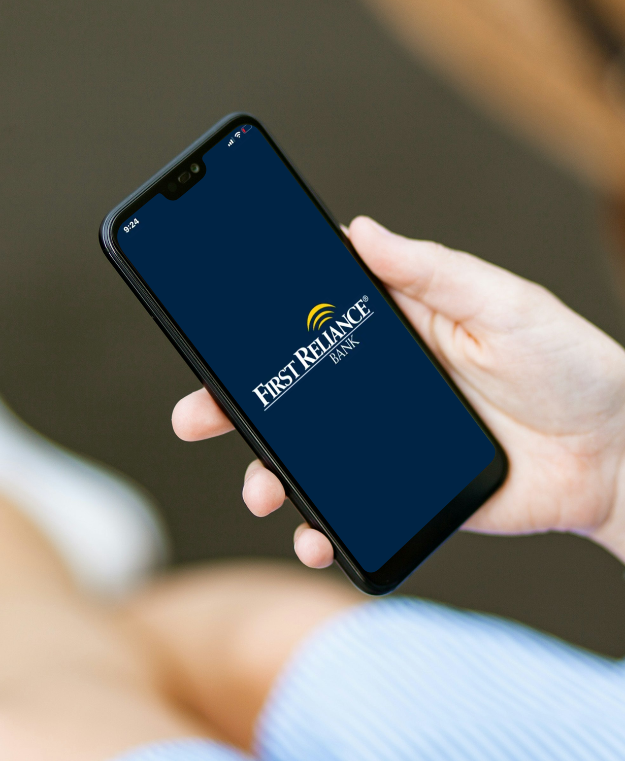 Hand holding a smartphone with First Reliance Bank logo