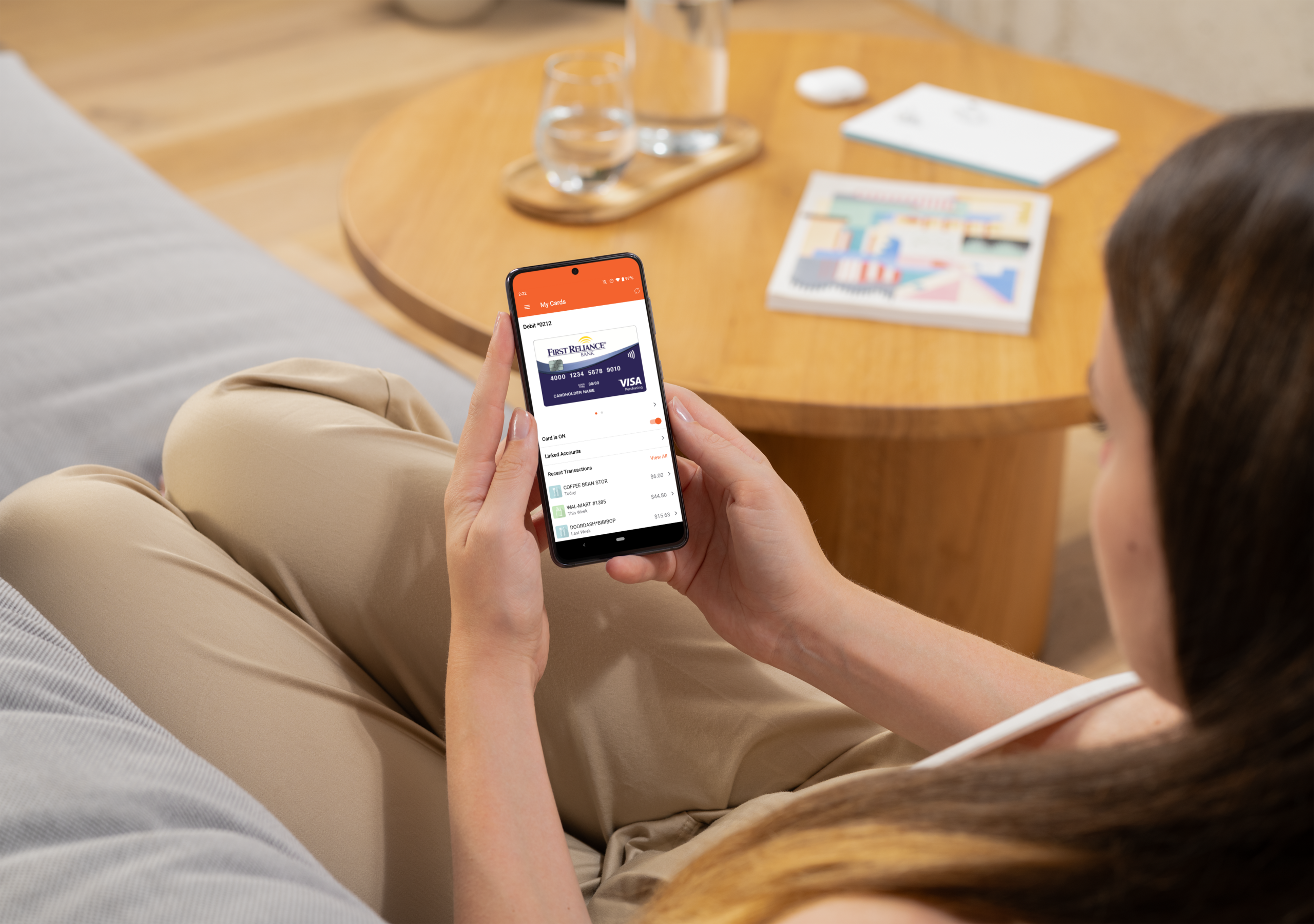 Woman holding a smartphone displaying First Reliance Bank’s credit card app